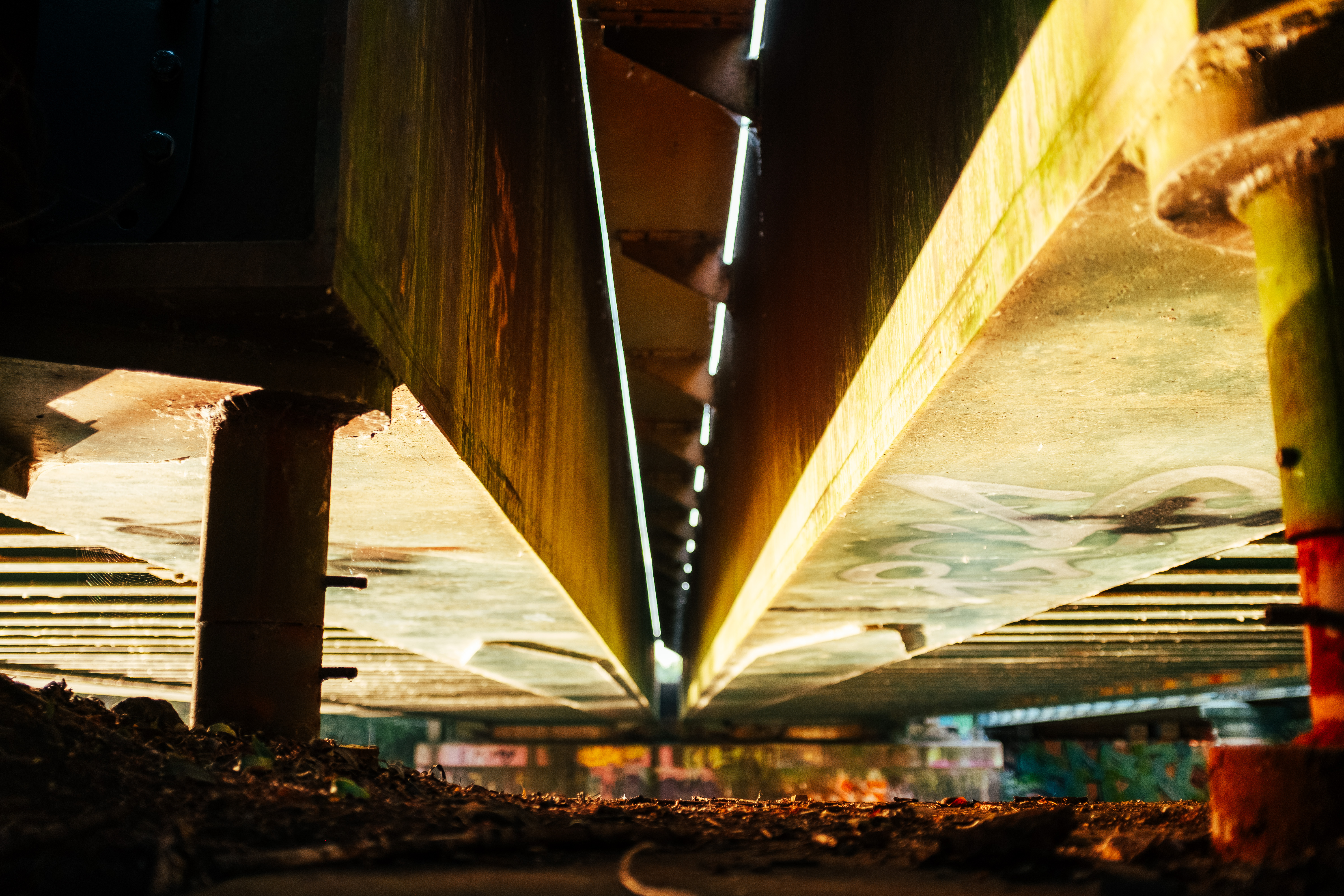 Rust and light under urban bridge.